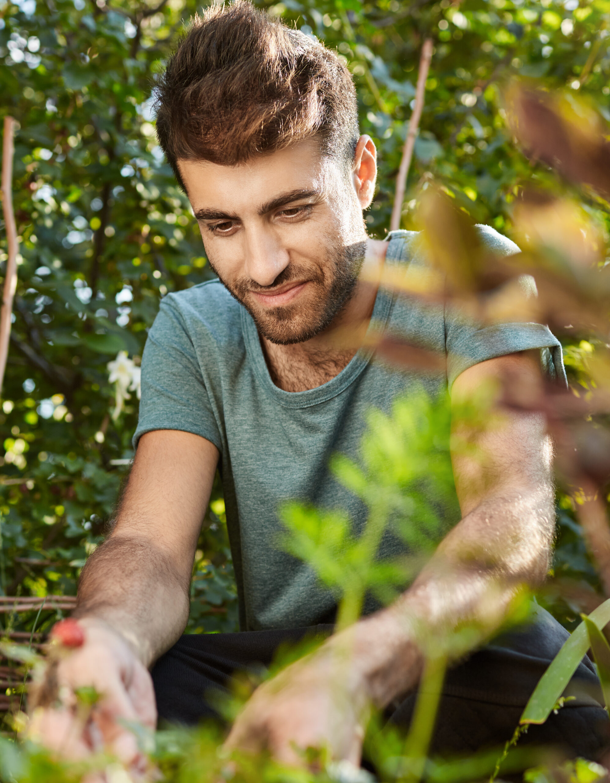 Close up outdoors portrait of happy mature bearded caucasian man smiling, working in garden near countryside house, picking berries, getting ready for healthy breakfast.